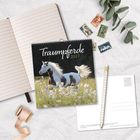 "Traumpferde 2027" auf einem Kalender mit Bild eines galoppierenden gescheckten Pferdes. Daneben liegen ein Notizbuch, Briefmarken und Postkarten.