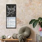 „TAFEL Zeiten“ steht auf einem Kalender. Darunter eine Tabelle. Daneben Sofa mit Kissen, Pflanze und Blumen.