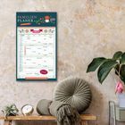 Der Kalender zeigt "Familien Planer", "Januar 2027". Daneben Pflanzen, Kissen und eine Uhr auf einem Tisch.