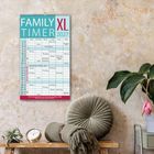 "FAMILY TIMER XL 2027" steht oben. Darunter Kalender mit Namen und Aktivitäten. Links Pflanzen, rechts Kissen und Uhr.