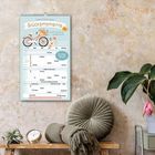 Text: "FAMILIENPLANER Glücksmomente 2027." Illustration: Fahrrad mit Blumen. Umgebung: Pflanze, Kissen, Uhr.