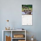 Ein Kalender an der Wand zeigt Mai 2027. Oben ist ein Foto von Elefanten an einem Fluss. Darunter ein weißes Regal.