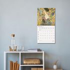 FEBRUAR 2027. Kalender mit Gemälde an der Wand; darunter ein Regal mit Büchern, einer Karaffe und Deko.
