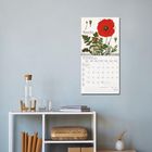 Kalenderseite von September 2027 mit Mohnblumengemälde an einer grauen Wand über einem weißen Regal.