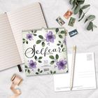 „Selfcare Katja Reiter 2027.“ Ein Kalender mit lila Blumen liegt neben einem Notizbuch, Briefmarken und einem Stift.
