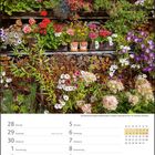 Kalender mit Daten von Juni und Juli 2027, abgebildet mit üppigen Blumen, die eine rustikale Holzfassade schmücken.