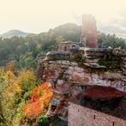 LAND UND LEUTE. Eine alte Burgruine über buntem Herbstwald auf einem Berg.