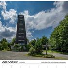 Juni/Juli 2027, 26. Woche. Rhein-Weser-Turm bei Kirchhundem-Oberhundem. Ein hoher Turm, umgeben von Bäumen und Wolken am Himmel.