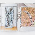 Links ein gemusterter Stoff auf einem Gestell. Rechts eine gefleckte Schnecke auf einem Boden mit eingravierten Buchstaben.