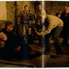 Ich kann keine spezifischen Texte im Bild erkennen. Es zeigt eine Filmszene mit einem Mann, der eine ältere Frau hält, umgeben von Kamera-Crew.