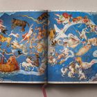 Illustration eines Nachthimmels mit mythologischen Figuren und Tieren auf blauen Seiten eines offenen Buchs.