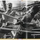 Zwei Boxer im Ring; einer schlägt zu, während der andere zurückweicht, begleitet von einem Schiedsrichter.