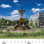 Schalenbrunnen auf dem Corneliusplatz in Düsseldorf. Viele Menschen im Park, blauem Himmel und modernen Gebäuden.