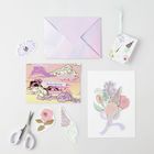 Ein Arrangement mit pastellfarbenem Briefumschlag, Blumenaufklebern und einer Karte mit "The Sky is the Limit".