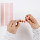 Drei rosa Papierstreifen und Hände, die rosa Papier falten.