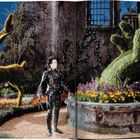 Die Seitenzahl "4" ist oben links. Eine Figur in einem schwarzen Outfit steht in einem Garten mit Hecken in Tier- und Handform.