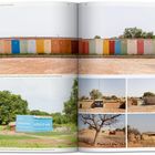 Seite mit Wandfarbtests und Häusern mit Werbeplakaten in einer ländlichen Umgebung.