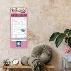 Text: "Familienplaner Kalender 2027." Eine Wand mit einem Kalender, daneben eine gemütliche Sitzecke mit Kissen und Pflanze.