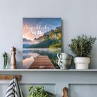 „Augenblicke der Stille“, 2024. Ein Kalender mit einem See, Bergen im Hintergrund, und einem Steg im Vordergrund.