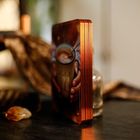 Ein Stapel Karten mit kupferfarbenem Rand, zeigt eine Hand, die eine Tasse mit dampfendem Getränk hält. Im Hintergrund unscharf.