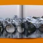 Offenes Buch mit Bild einer Brücke, von Felsen bedeckt. Hintergrund zeigt einen klaren Himmel und Gebäude.