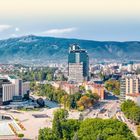 "SOFIA UND UMGEBUNG" steht oben. Eine städtische Szene mit hohen Gebäuden, grüner Parkanlage und Bergen im Hintergrund.