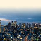 Text: "TŌKYŌ UND KANTŌ". Ein Stadtpanorama bei Nacht mit beleuchteten Gebäuden und einem dämmernden Himmel.