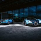 Zwei blaue Sportwagen stehen vor einem modernen Gebäude mit Glasfassade.