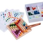 Auf Karten sind bunte Punktmuster zu sehen. Daneben ein Holzbrett mit bunten Kugeln, eine Box mit Kugeln und eine Zange.