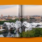 Ein Panorama von Paris mit Blick auf die Seine, die mit weißen Stoffbahnen bedeckte Brücke und den Eiffelturm im Hintergrund.