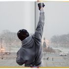 Ein Mensch mit erhobenem Arm steht vor schneebedeckter Landschaft, von hinten in einer offenen Buchdarstellung.
