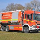 Feuerwehr Eching, AB-Wasser Schaum steht auf einem großen, roten Feuerwehrfahrzeug. Es steht auf einer grünen Wiese.