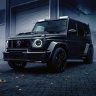 Ein SUV steht vor einer Garage. Er hat große, schwarze Räder und eine kantige, robuste Form.