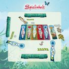 „Spielinhalt“ in roter Schrift oben. Illustration von bunten Spielfeldern und Spielsteinen mit Blumenmotiven auf grünem Hintergrund.