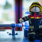 Ein Teddybär namens Konrad trägt eine Feuerwehruniform und sitzt auf einem blinkenden blauen Licht.