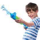 Ein Junge in einem blau-weiß gestreiften T-Shirt spritzt lächelnd Wasser mit einer blauen und grünen Wasserpistole.