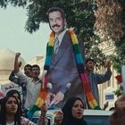 Menschenmenge mit Plakaten, darunter ein großes Porträt eines Mannes in einem farbigen Schal, feiernd auf der Straße.