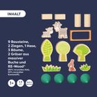 INHALT: 9 Bausteine, 2 Ziegen, 1 Hase, 3 Bäume, 2 Gräser. Abgebildet sind Holzblöcke und Tierfiguren.