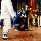 Mehrere Männer in traditionellen asiatischen Outfits in einer kämpferischen Szene auf rotem Fliesenboden.