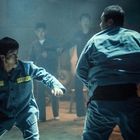 Uniform mit gelbem Etikett "1552". Männer in blauen Overalls, angespannte Stimmung, eine Auseinandersetzung.