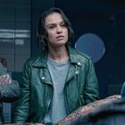 Keine Texte sichtbar. Drei Personen in einem Raum, eine in Krankenhauskleidung, die anderen in Freizeitkleidung.