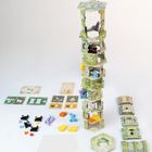 Spielkarten zeigen Tier-Silhouetten. Ein hoher Turm aus sechseckigen Platten, umgeben von bunten Tierfiguren und Karten.