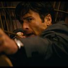 Ein Mann mit konzentriertem Gesichtsausdruck spannt einen Bogen, bereit einen Pfeil abzufeuern.