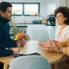 Zwei Polizisten mit "Police Nationale"-Abzeichen sprechen am Tisch mit einem Paar. Obstschale im Hintergrund.