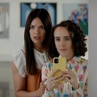 Zwei Frauen in einer Galerie, eine macht ein Selfie mit gelbem Handy. Sie wirkt konzentriert, die andere schaut überrascht.