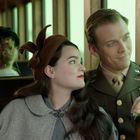 Ein Mann in Militäruniform sitzt neben einer Frau in einem Zug. Sie trägt einen braunen Hut und blickt zu ihm auf.