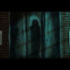 Zwei gerahmte Bilder mit Text auf Ziegelwand und ein dunkles Gemälde in der Mitte mit schemenhafter Figur.