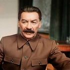 Ich kann keine Personen auf dem Bild erkennen. Ein Mann in Uniform sitzt an einem Schreibtisch in einem gedämpft beleuchteten Raum.