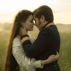 Ich sehe keinen Text. Ein Paar in liebevoller Umarmung vor einer nebligen Wiese im Morgenlicht.