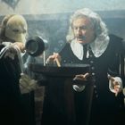 Zwei Männer in historischer Kleidung, einer mit weißer Maske, stehen nebeneinander und rühren in einem großen Kessel.